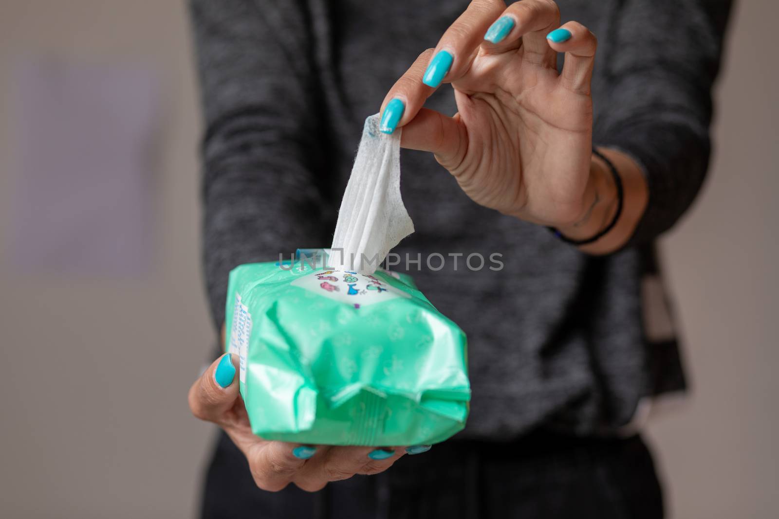 Old woman hand with turquoise nails taking the wet wipe to clean skin or surface stock photo