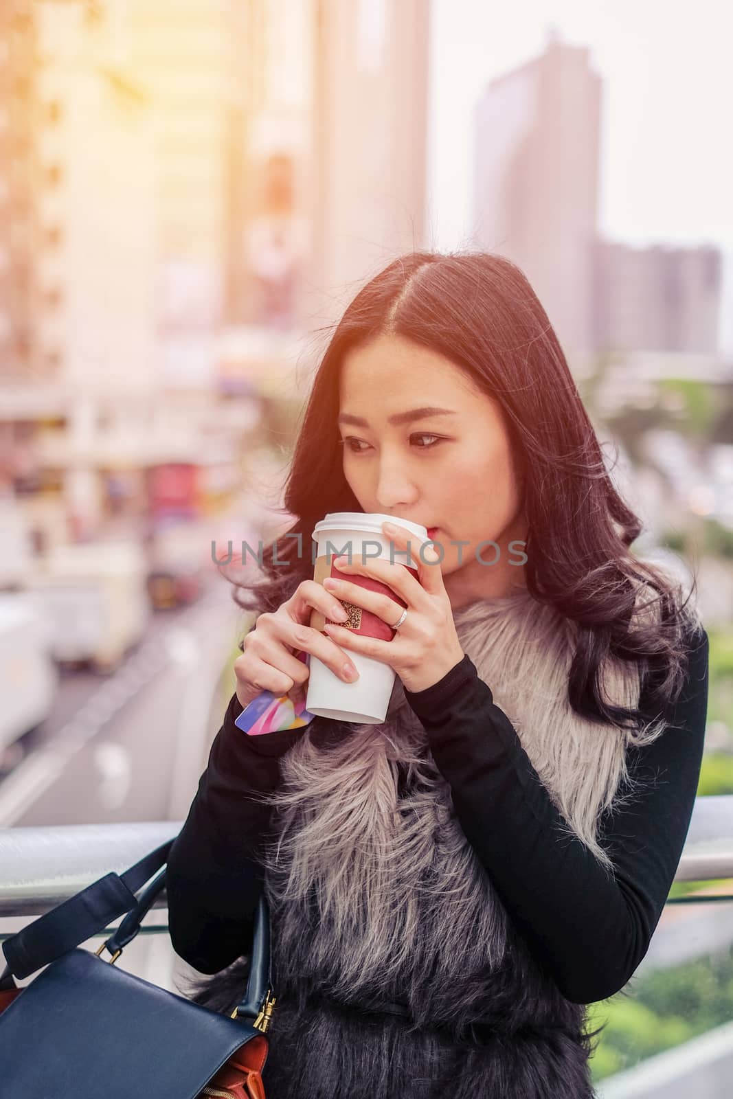 Woman drinking coffee at outdoor street with sunrise streaming 
