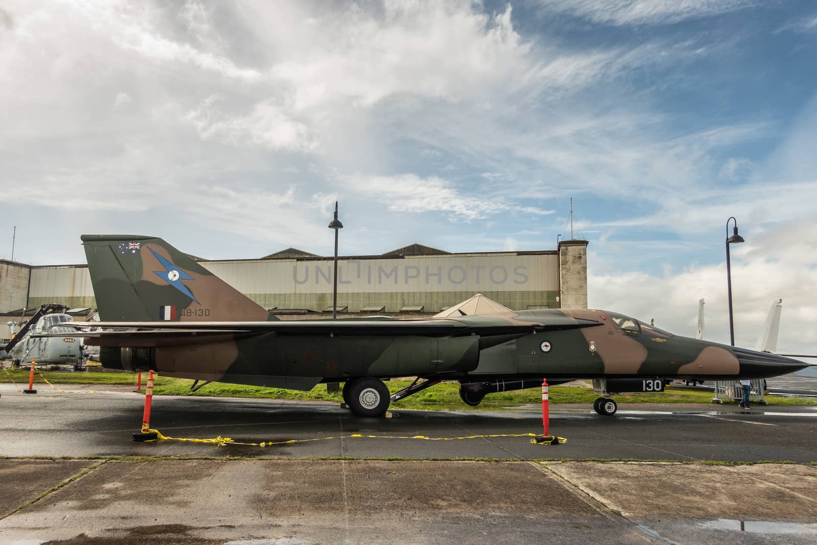 Oahu, Hawaii, USA. - January 10, 2020: Pearl Harbor Aviation Museum. Original Genral Dynamics F-111C model A8-130 fighter jet on tarmac near hangar under blue cloudscape. RAAF owned.