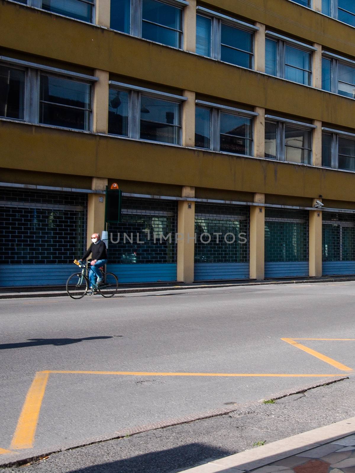 Cremona, Lombardy, Italy - May  5 6 7  2020 - man or woman walking or biking in deserted downtown  during covid outbreak lockdown phase 2