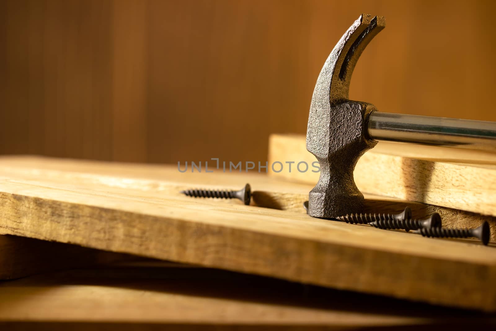 Hammer and screw on lumber in lighting and shadow of the sunshine in morning. The concept of woodcraft or carpentry.