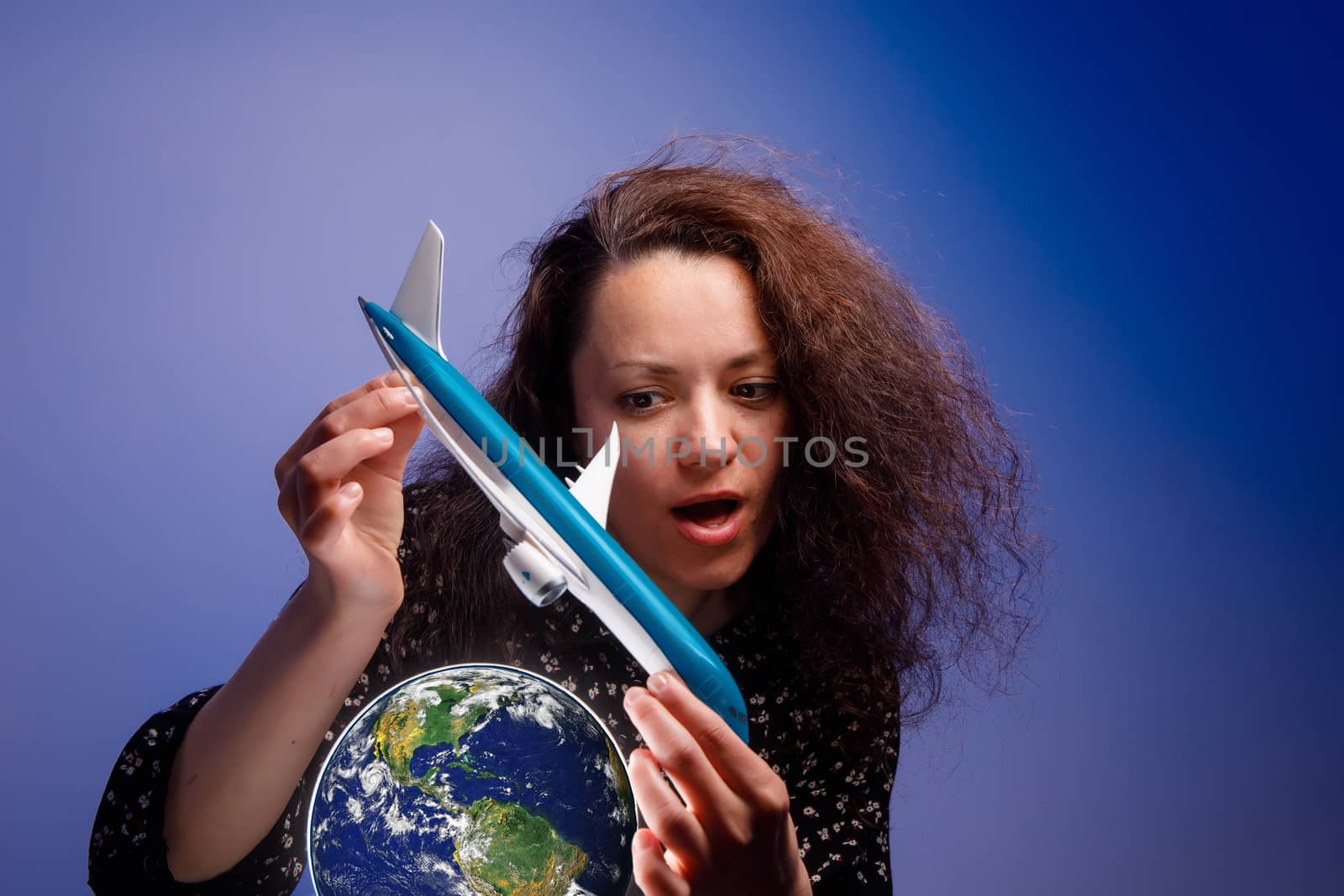 Girl with an airplane model in her arms over an earth globe. Concept of Airline help