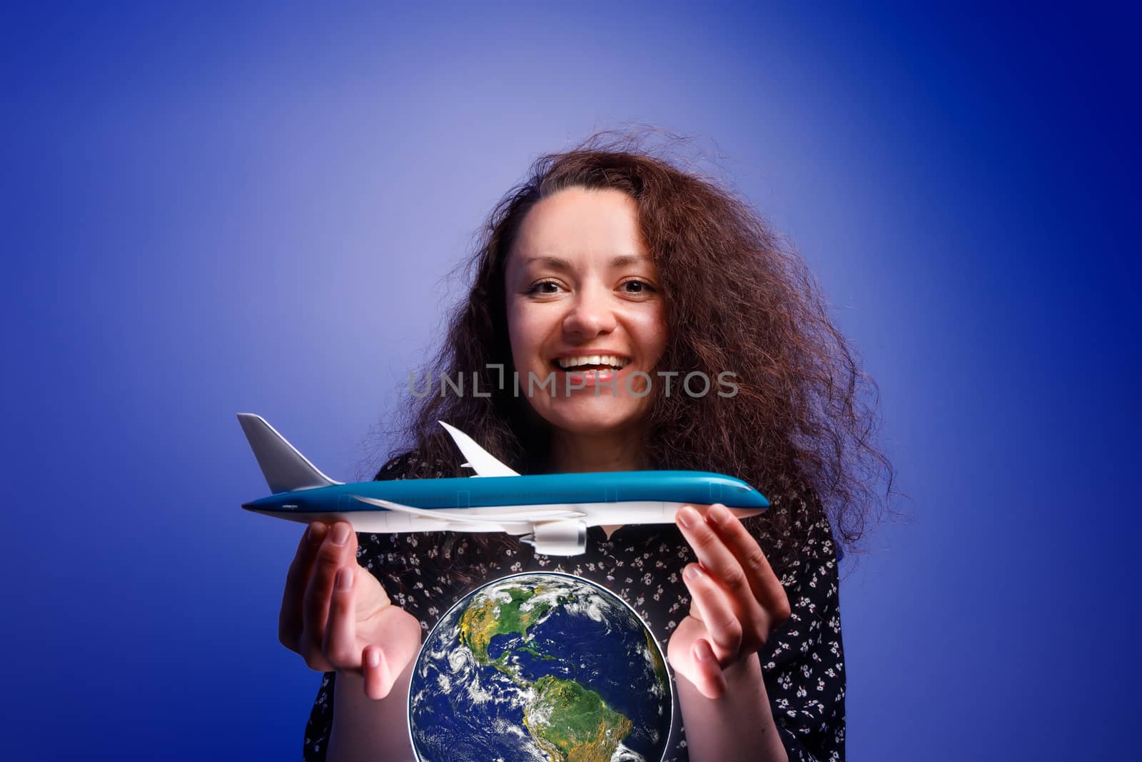 Girl with an airplane model in her arms over an earth globe. Concept of Airline help