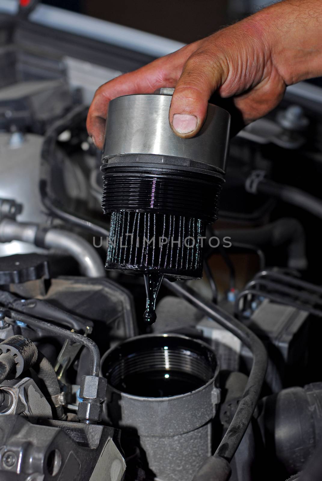 Repairman holding the old oil filter by car