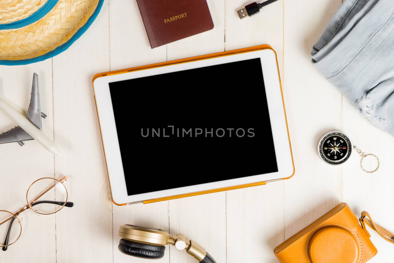 Blank tablet surrounded by summer travel equipment