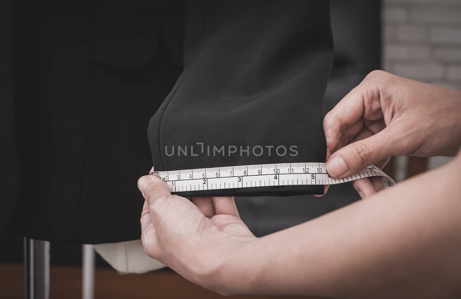 Clothing stylist is measuring jacket sleeve by junce