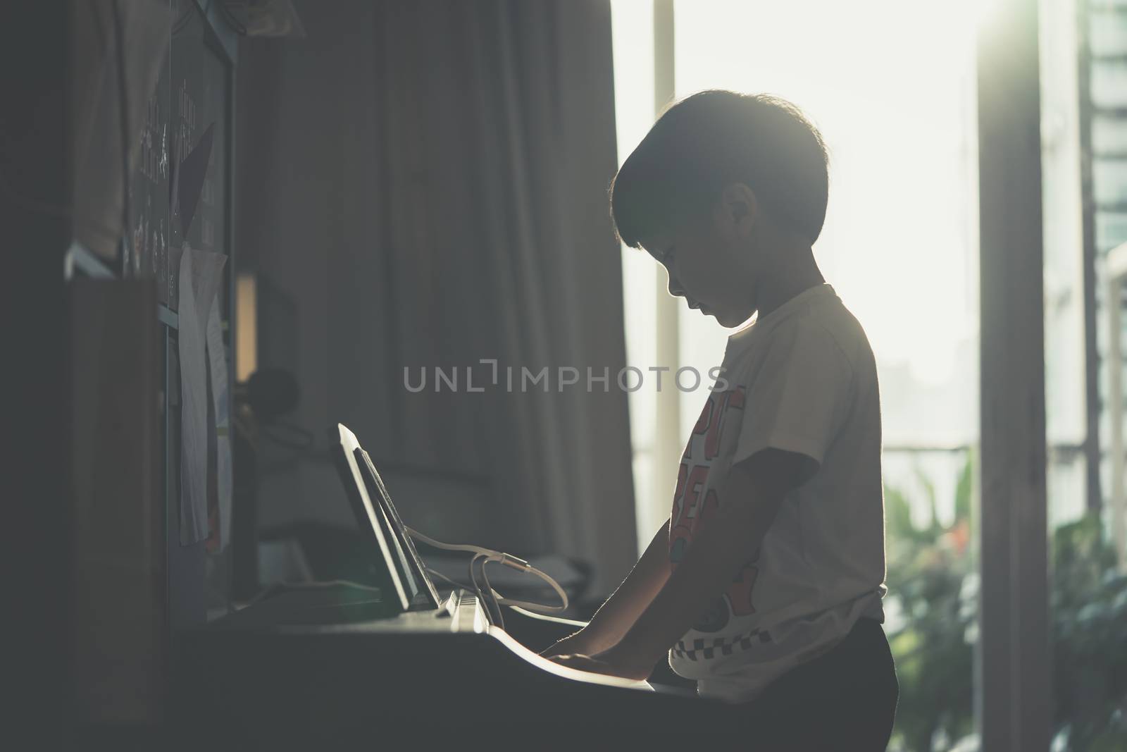 Little Boy is playing with piano and Music Tablet at home by junce