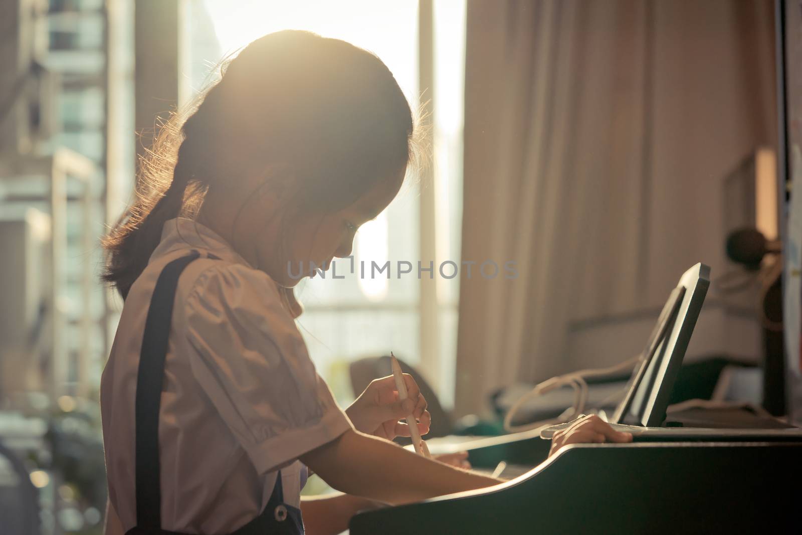 Little girl is playing with piano and Music Tablet at home
