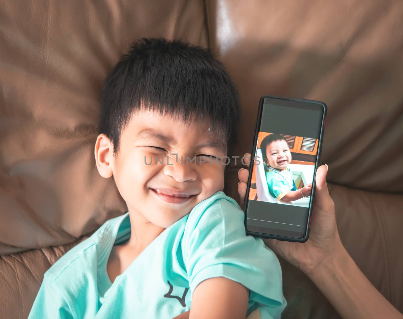 Boy comparing himself with his own baby picture