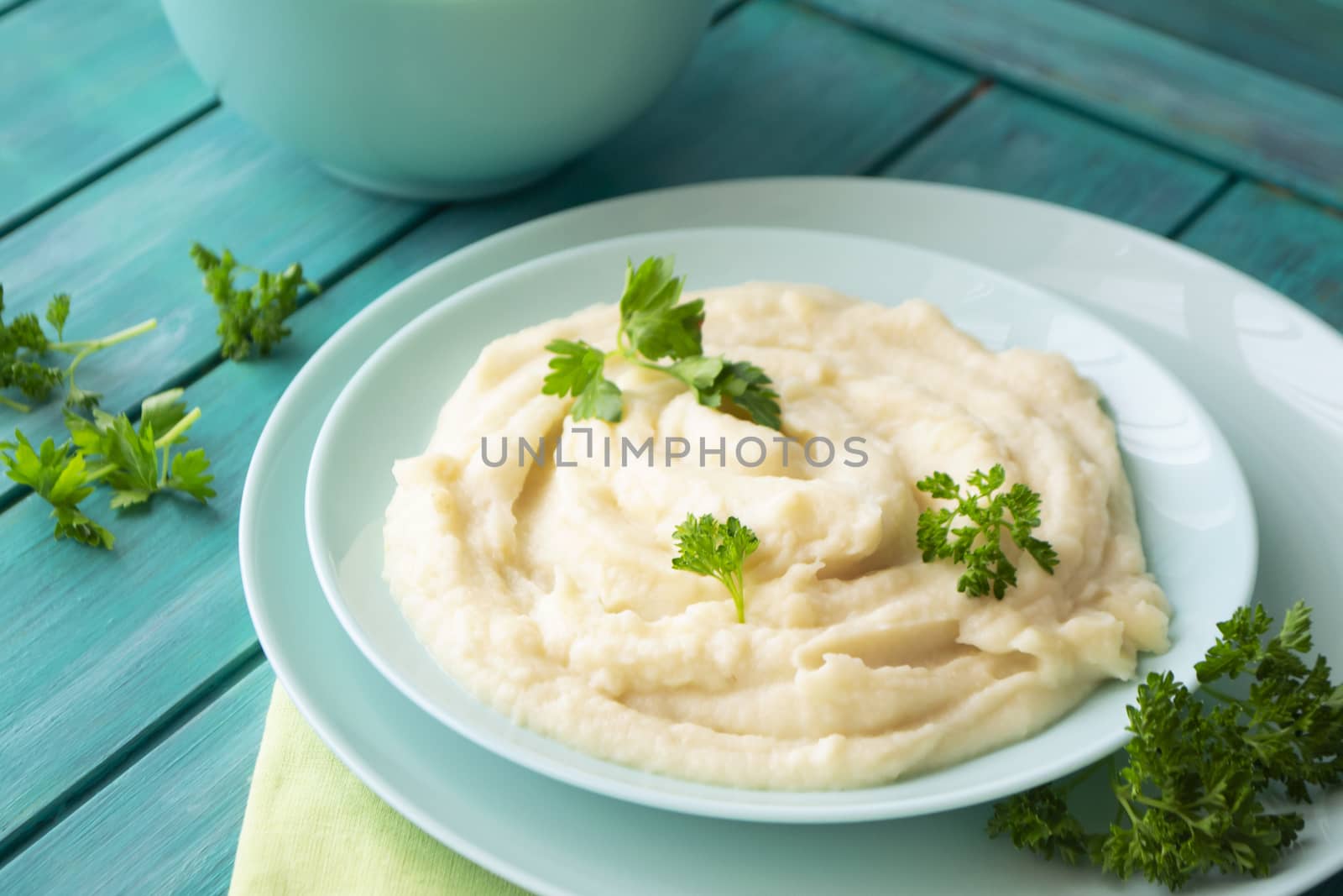 Mashed pureed potato in bowl on wooden table with persil