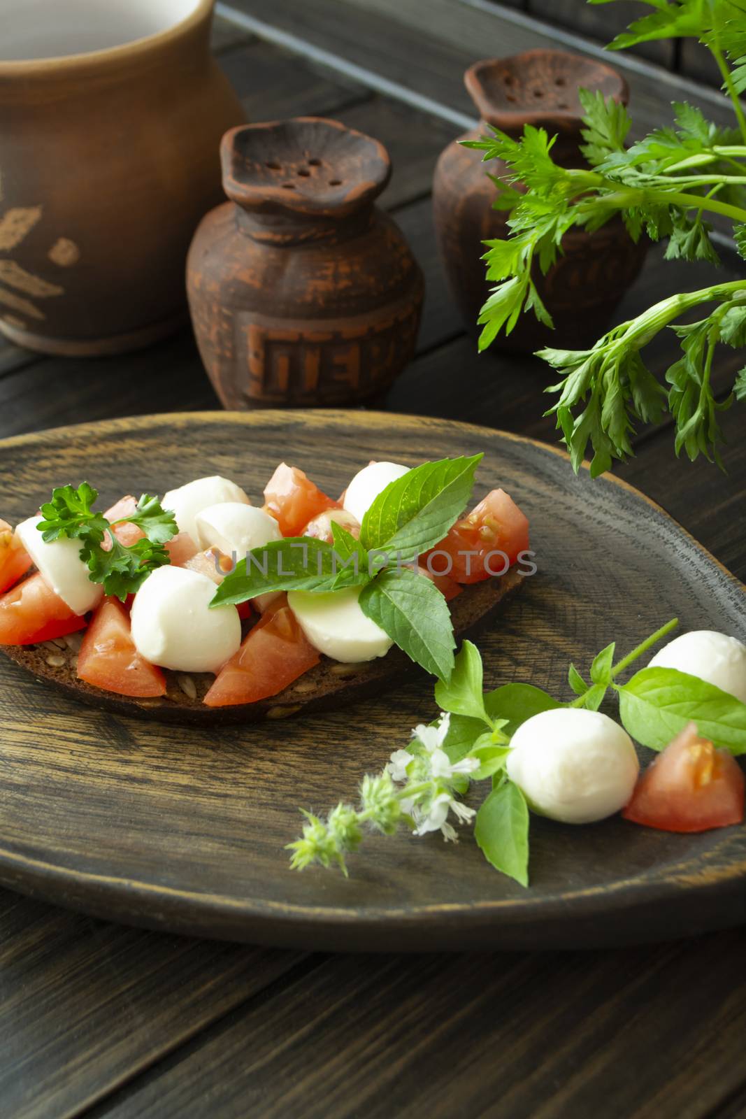 Bruschetta with red tomatoes, mozzarella cheese and basil on a old rustic dark table. Vertical image