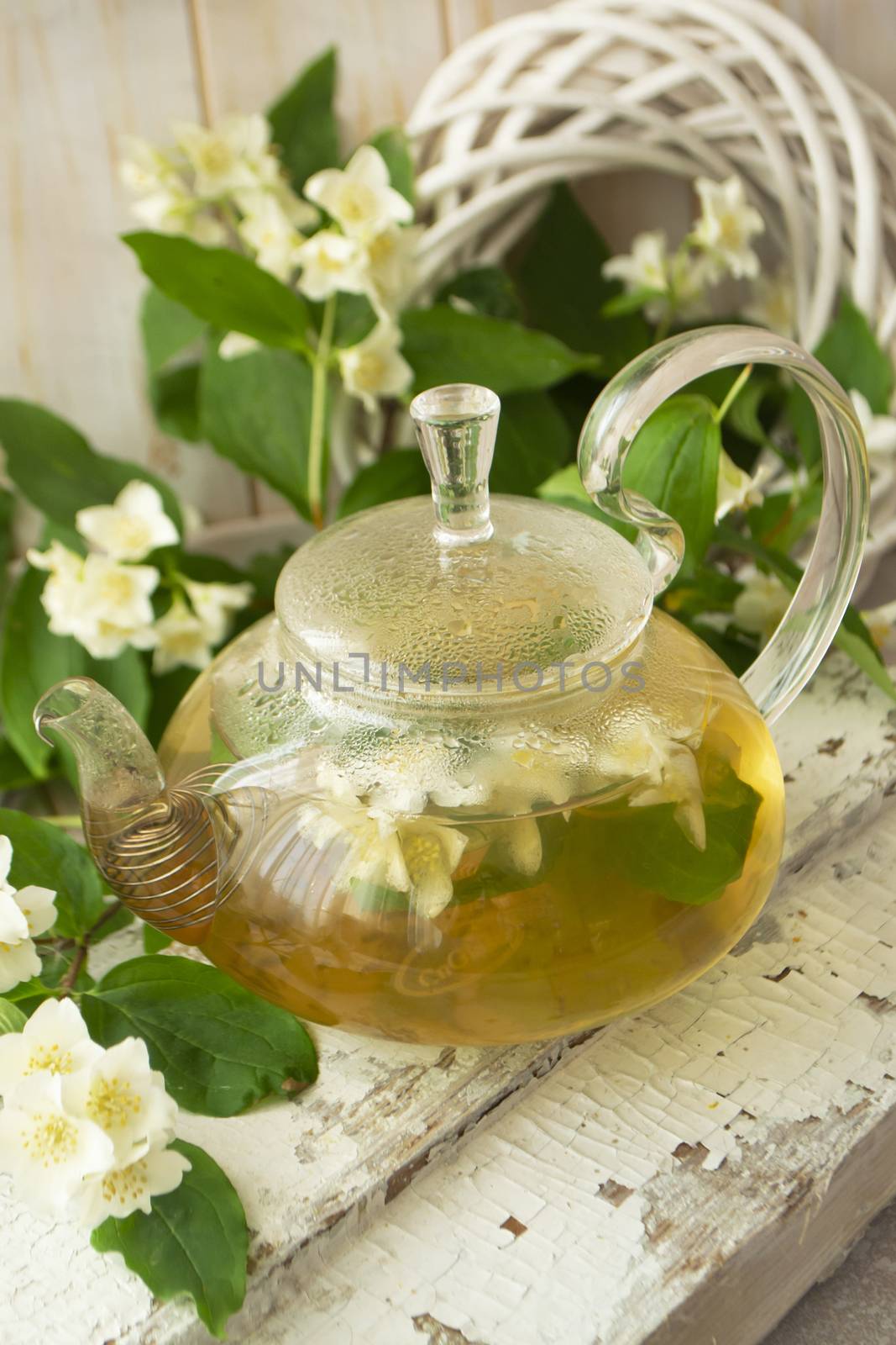 green tea with jasmine in glass teapot on wooden shabby table, vertical image