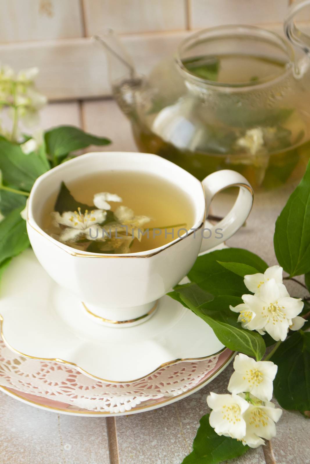 Jasmine tea with jasmine flowers on white wooden table background. Cup of hot green tea with jasmine flavor, fresh jasmine flowers. Concept of freshly drink. Vertial image