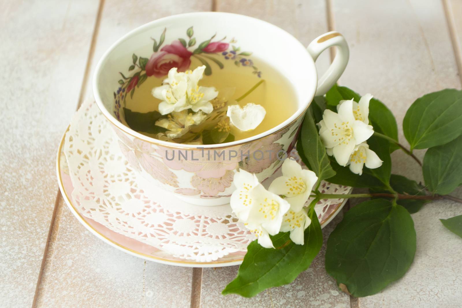 A cup of green tea with jasmine flowers. Fresh jasmine branches. Vintage classic cup