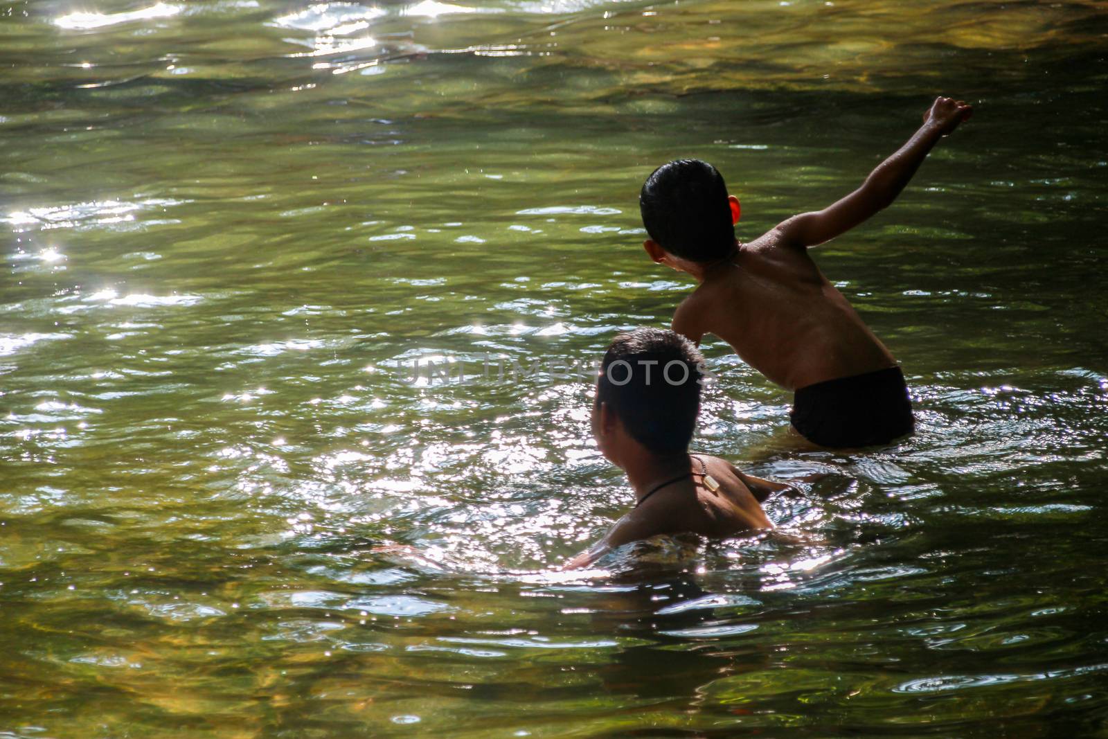 Two boys playing in the water by suthipong