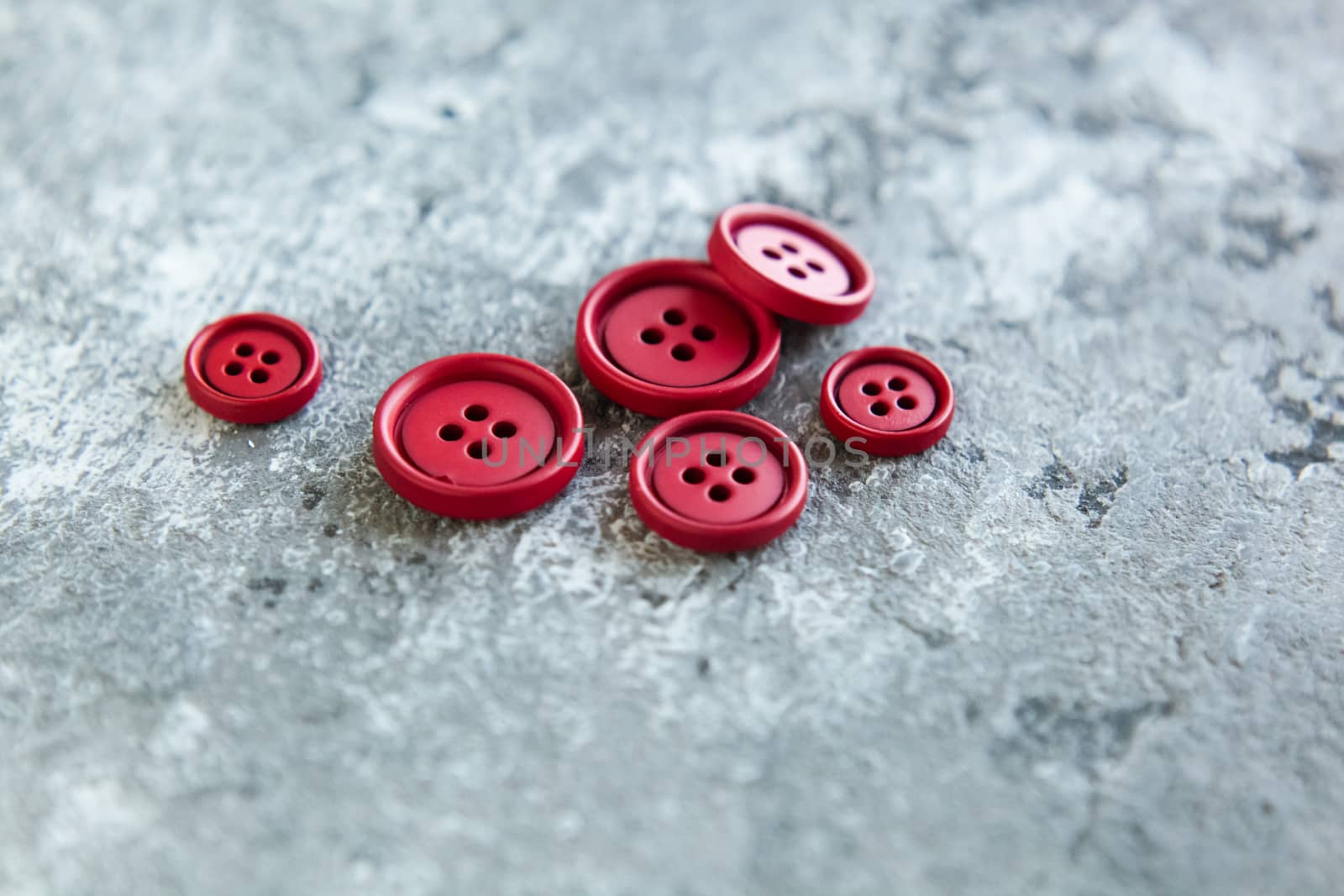 Pile of red matte buttons on concrete background, macro bokeh. beautiful needlework