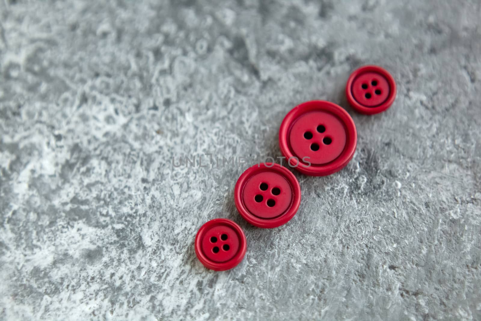 Pile of red matte buttons on concrete background, macro bokeh. beautiful needlework