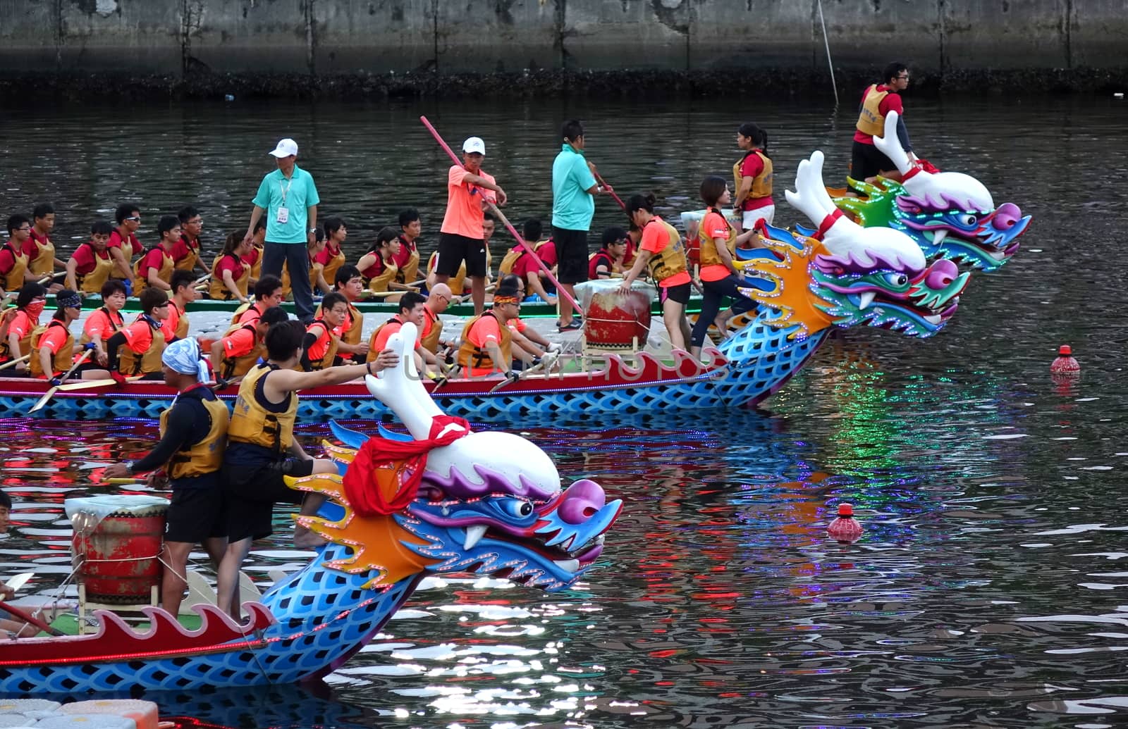 KAOHSIUNG, TAIWAN -- MAY 30, 2017: Three unidentified teams compete in the Dragon Boat Races on the Love River in Taiwan in the evening.