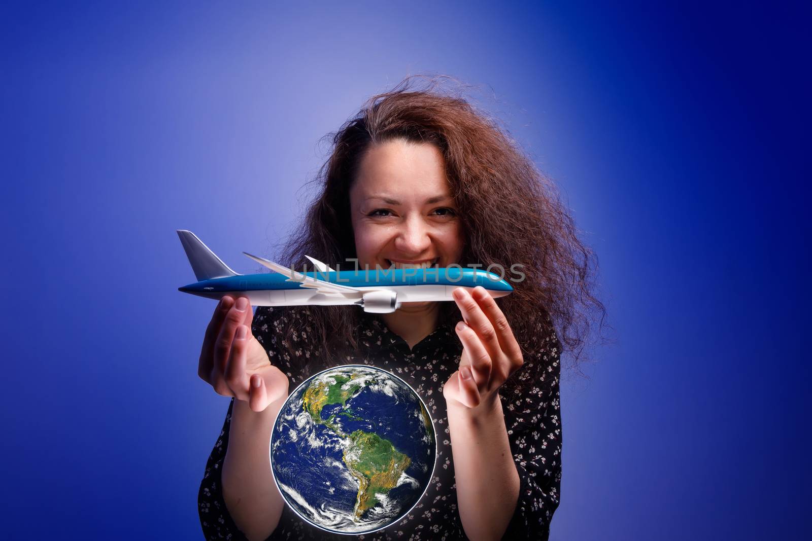 Girl with an airplane model in her arms over an earth globe. Concept of Airline help