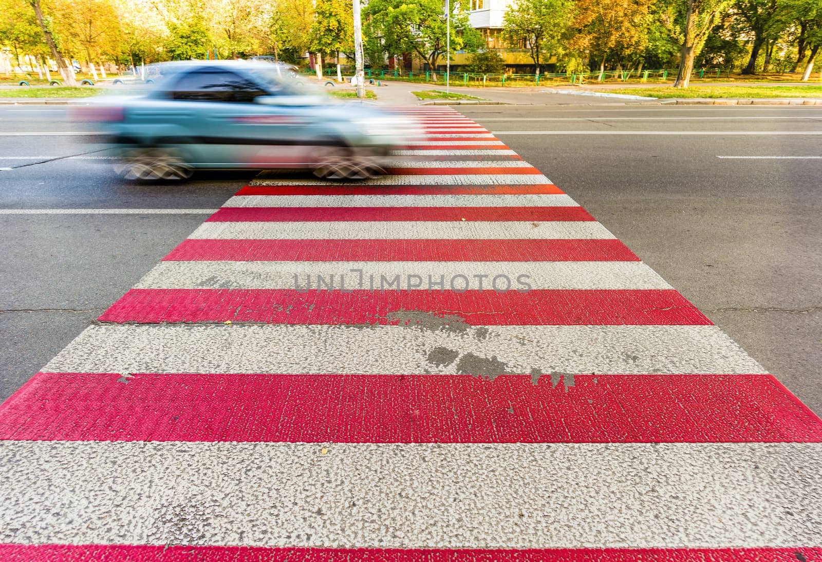 Gray car on a  red and white pedestrian crossing on blue black asphalt in the town of Kiev, Ukraine