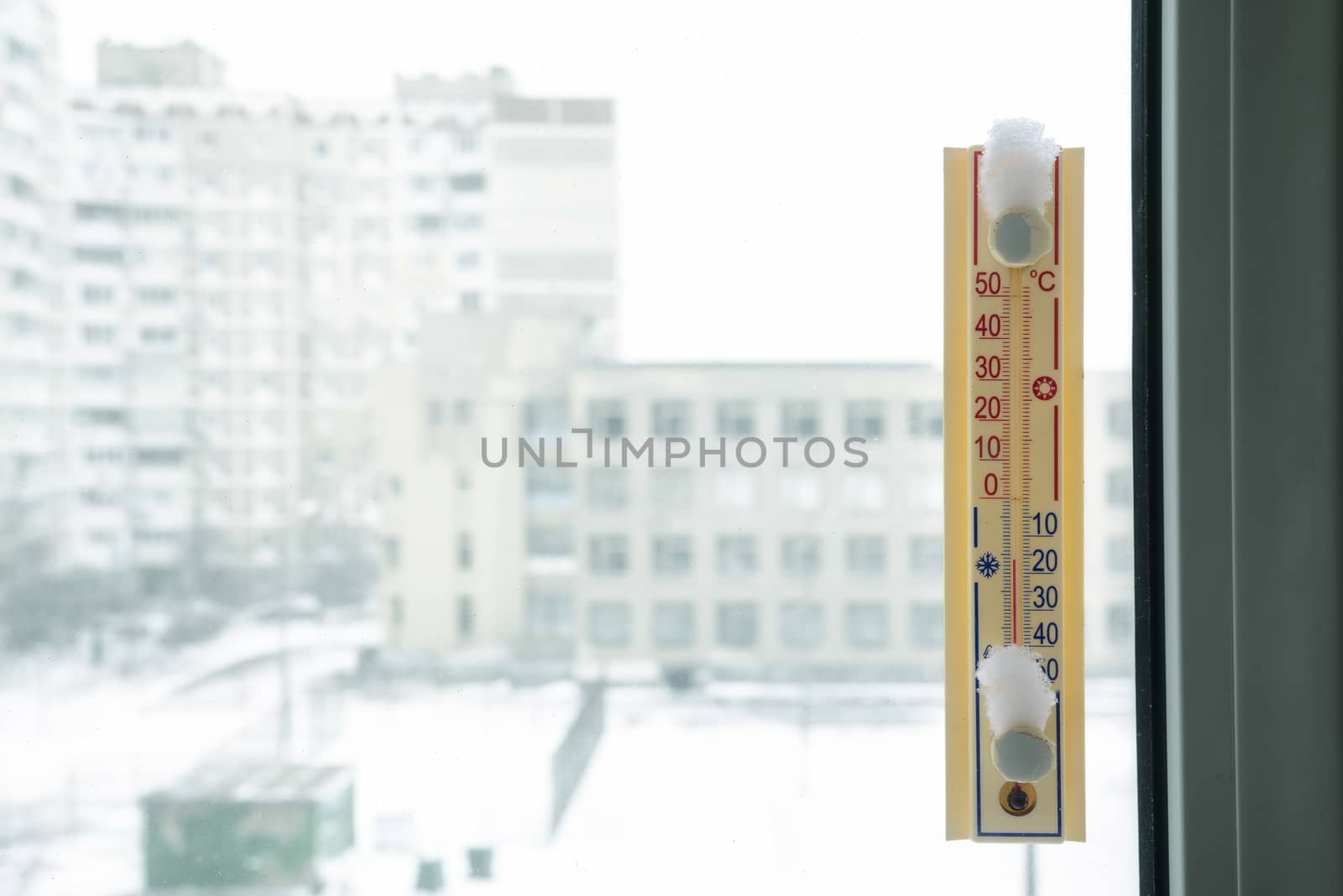 A thermometer, fixed out of the window, shows that it is minus seventeen degree celsius outdoor, while it is warm inside the room