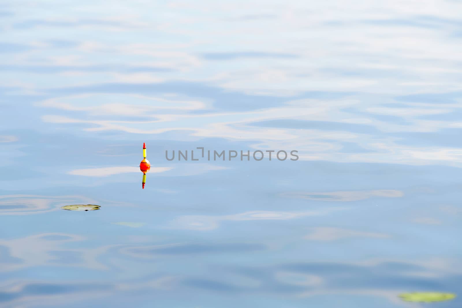 A yellow and orange fishing float in blue water