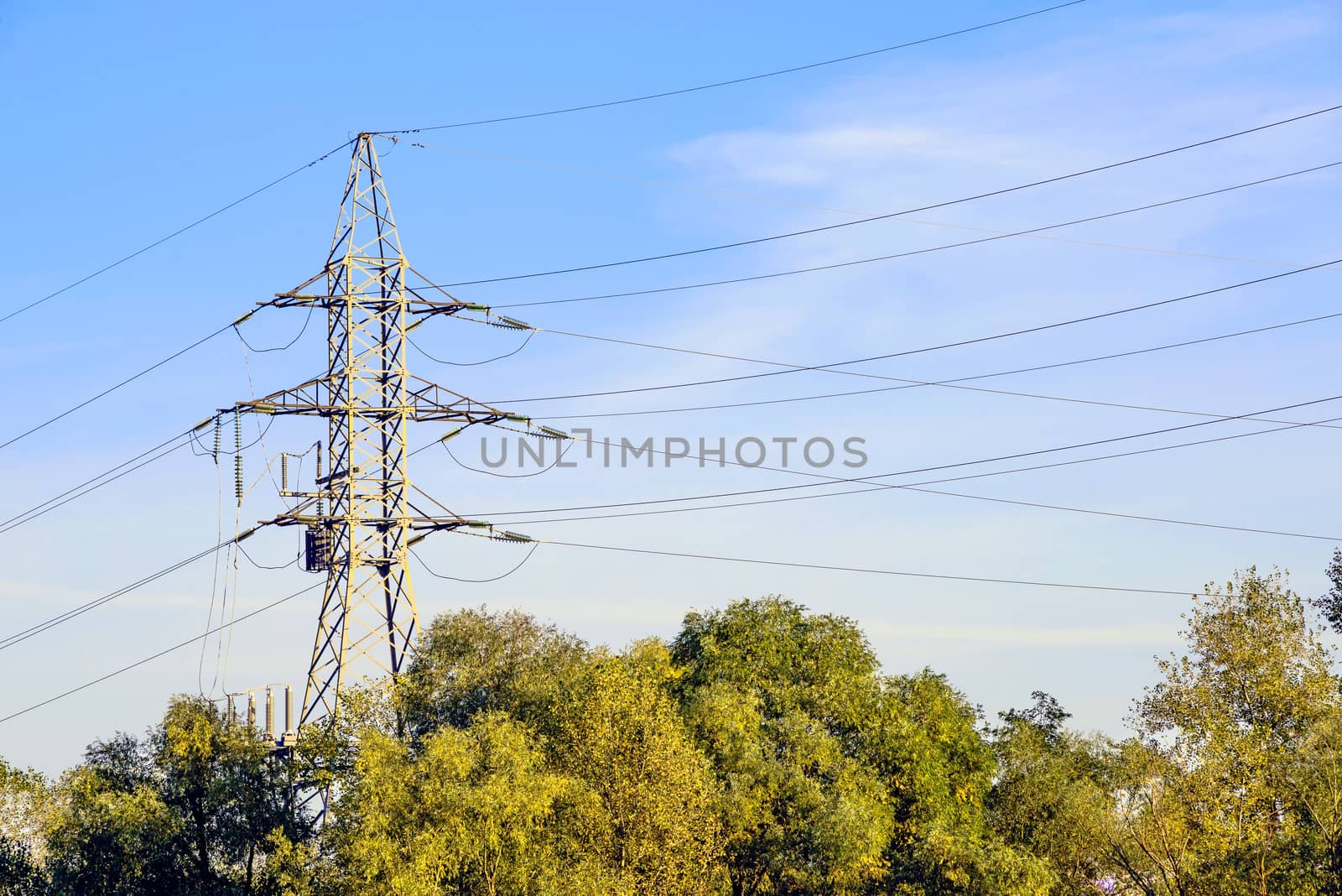 Electricity pylon against blue sky: high voltage electric cables seen from below . Room for text