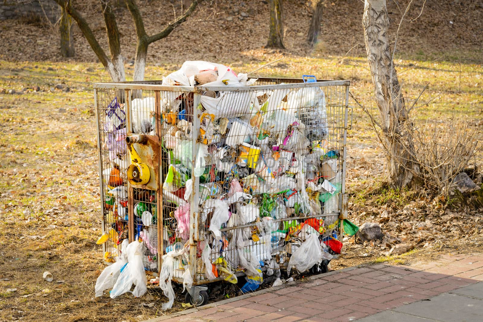 Metallic garbage container full of trash, outdoor in the country