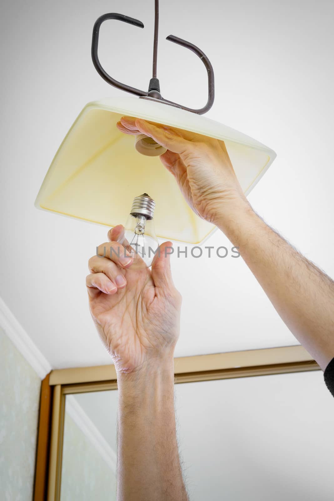 Man installing or changing a bulb, fixing it to the socket at home