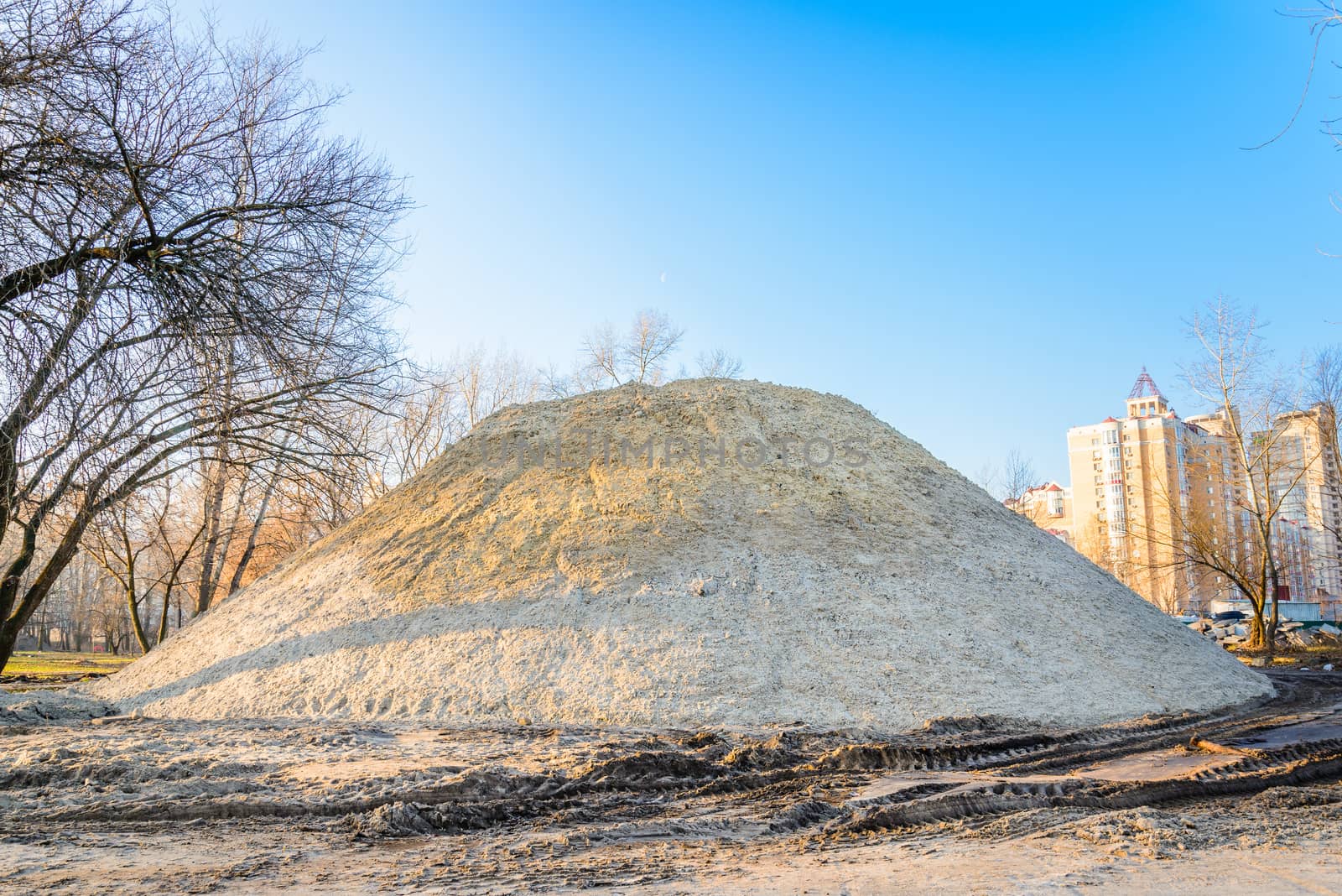 A huge sand heap during construction in the park at sunrise