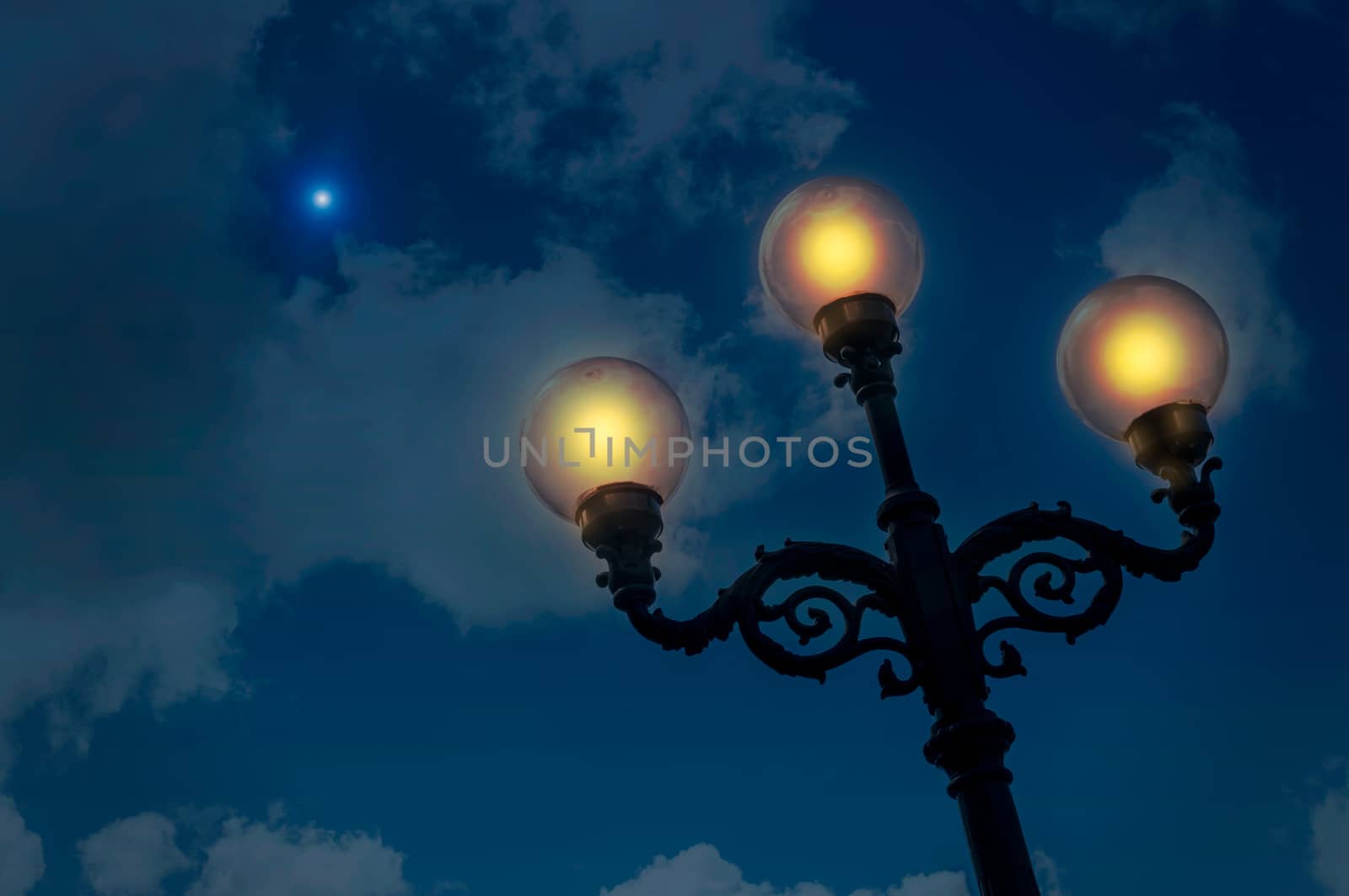 A lantern with three lamps illuminates a starry and cloudy night