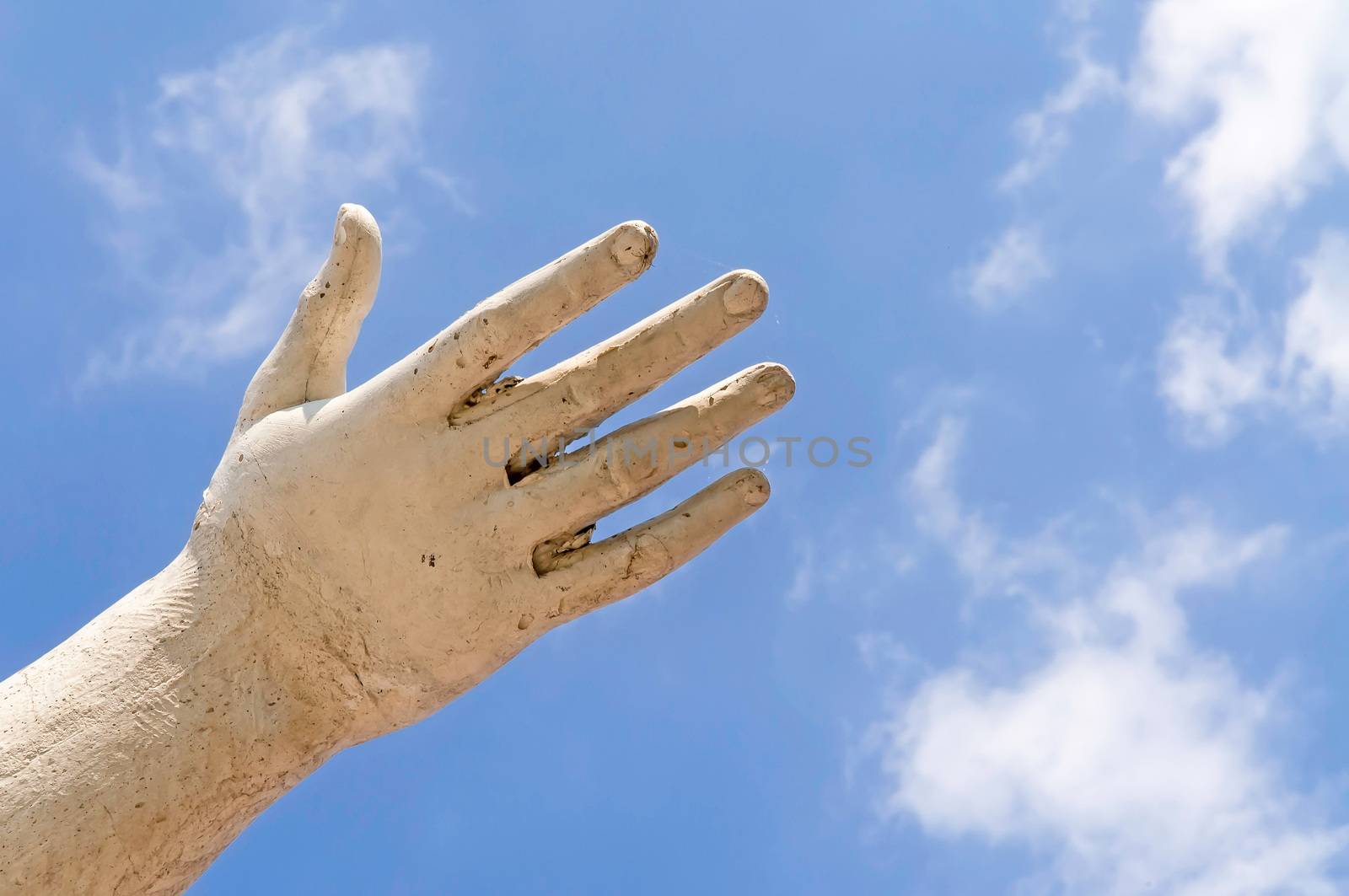 A statue hand showing the white clouds in the blue sky, as idea of freedom