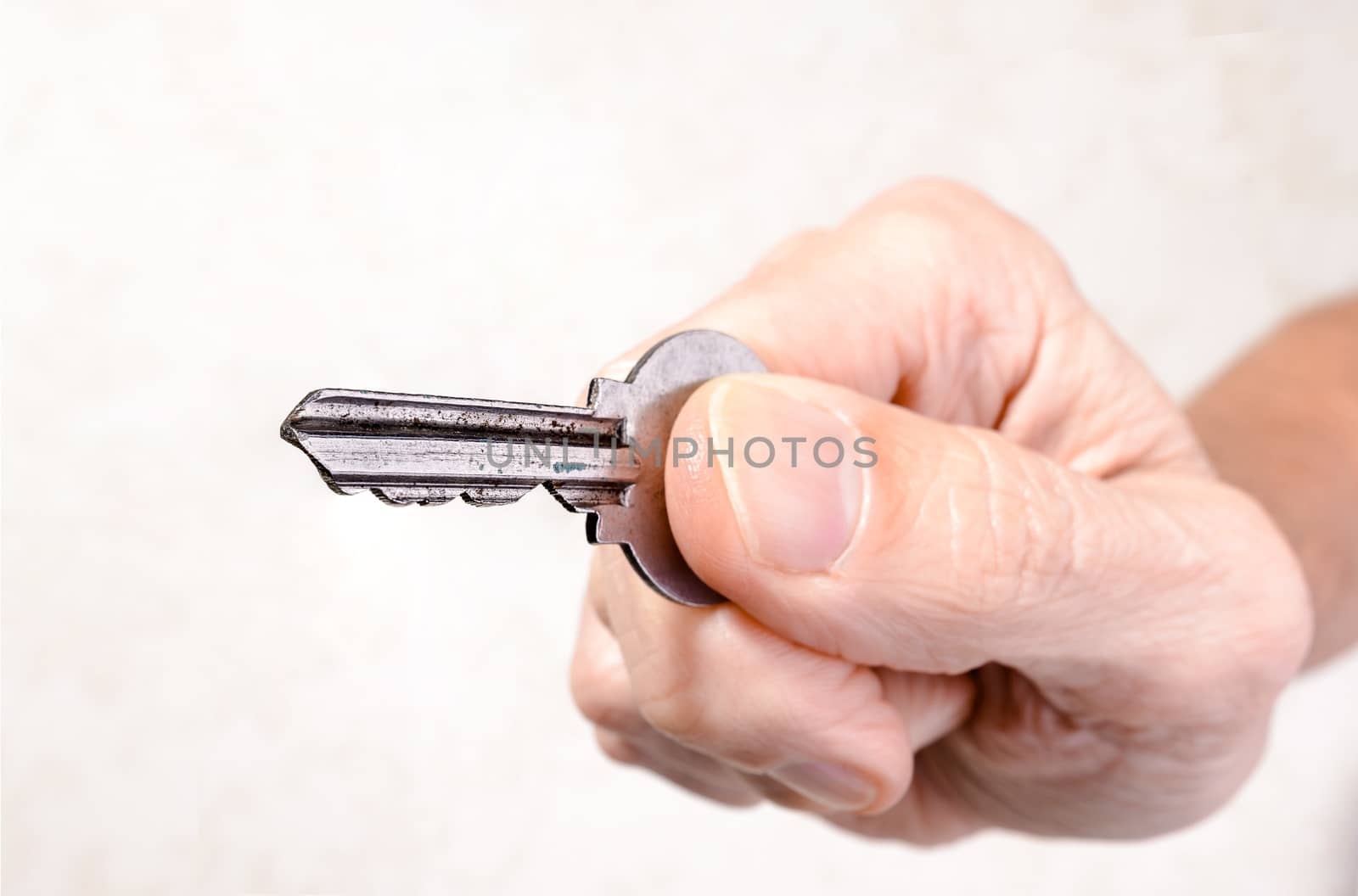 A man's hand is holding a key, opening or closing a door, on light background