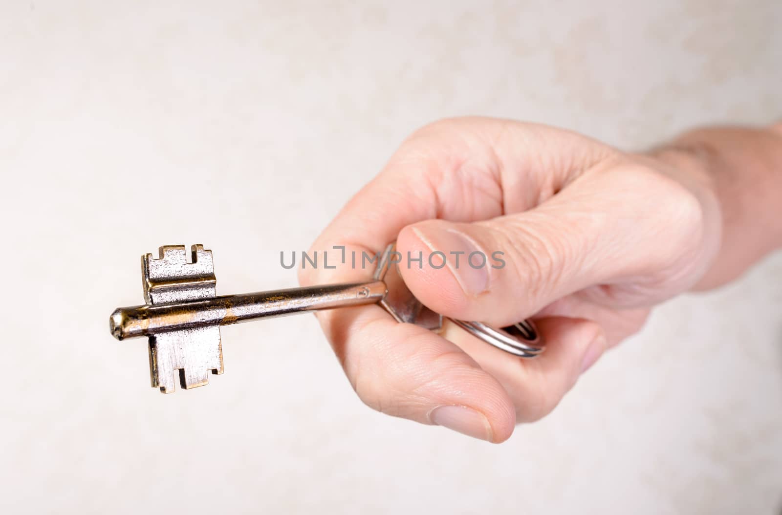 A man's hand is holding a key, opening or closing a door, on light background