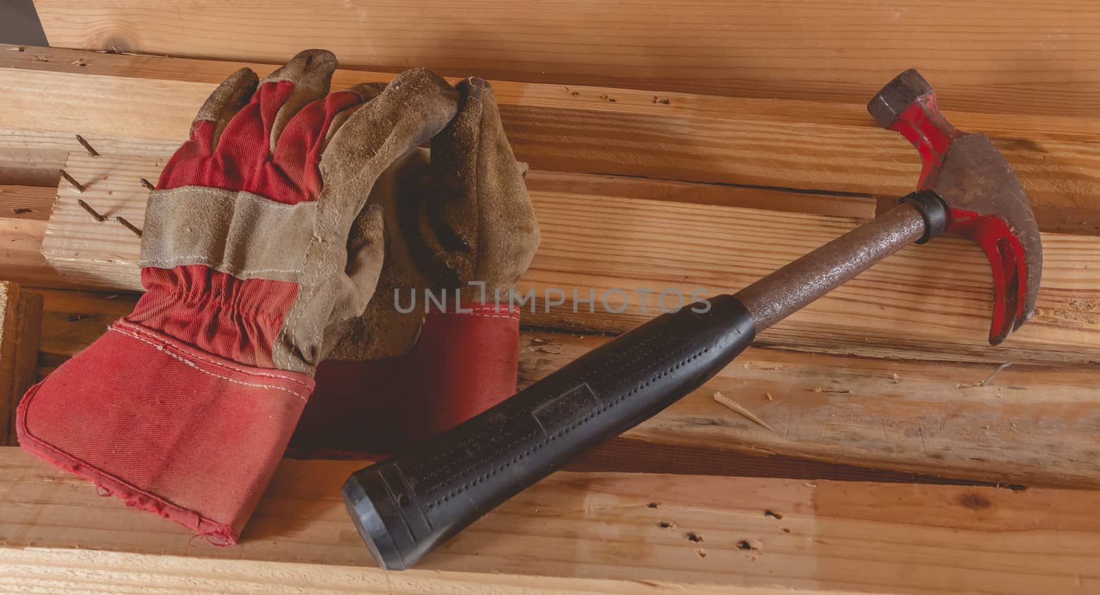 old rusty hammer and construction gloves laid on wooden board in studio