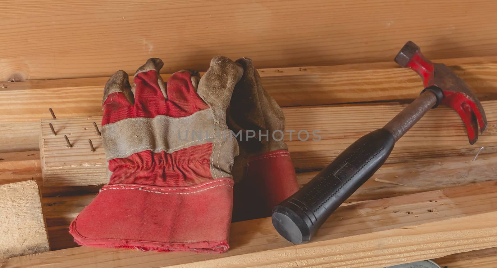 old rusty hammer and construction gloves laid on wooden board in studio