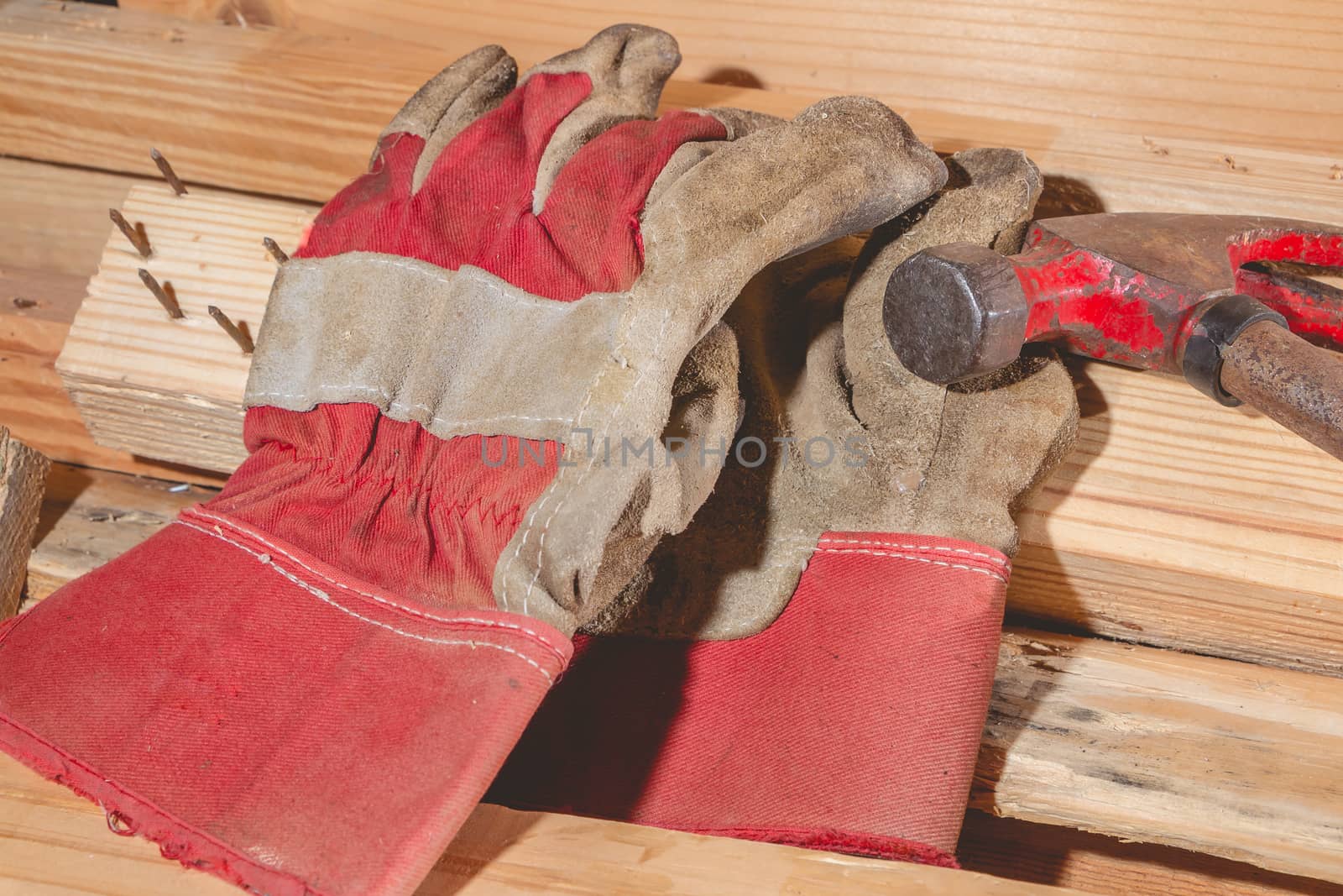 old rusty hammer and construction gloves laid on wooden board in studio