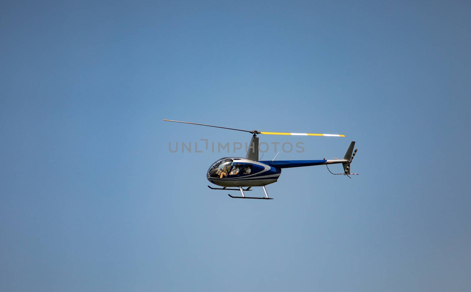 Robinson 44 Raven II helicopter at flight on clear blue sky by mkenwoo