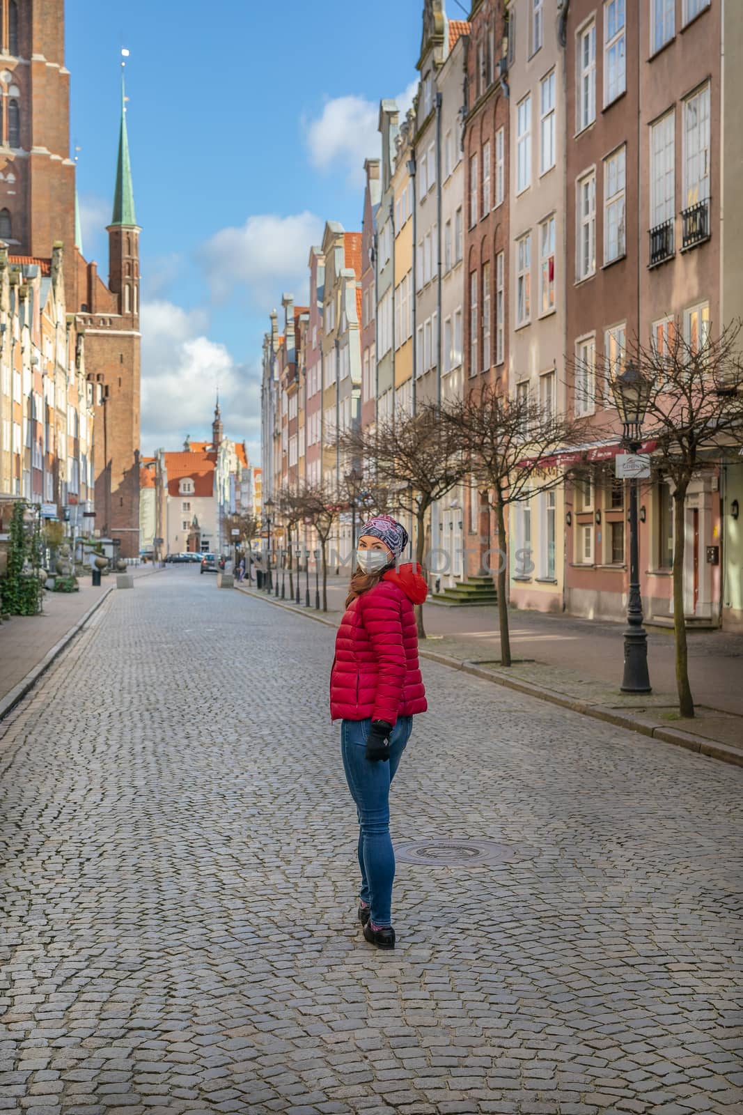 Woman in mask during corona virus (COVID-19) outbreak walking on the streets of Old Town Gdansk, Poland by mkenwoo