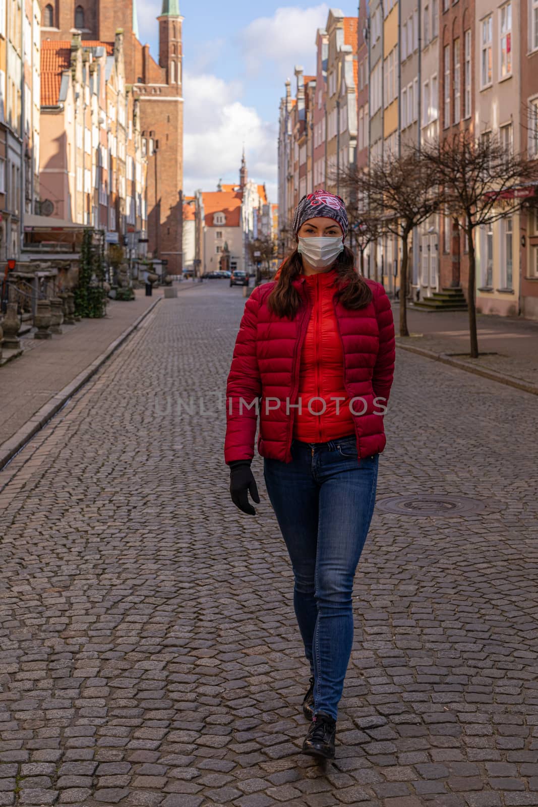 Woman in mask during corona virus (COVID-19) outbreak walking on the streets of Old Town Gdansk, Poland by mkenwoo