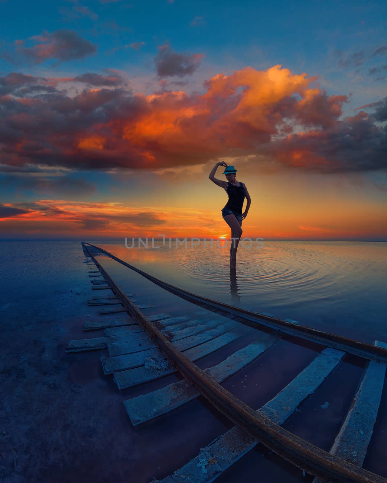 Woman at beauty sunset on salty lake with railway, concept of vacation at home, local tourism or domestic tourism