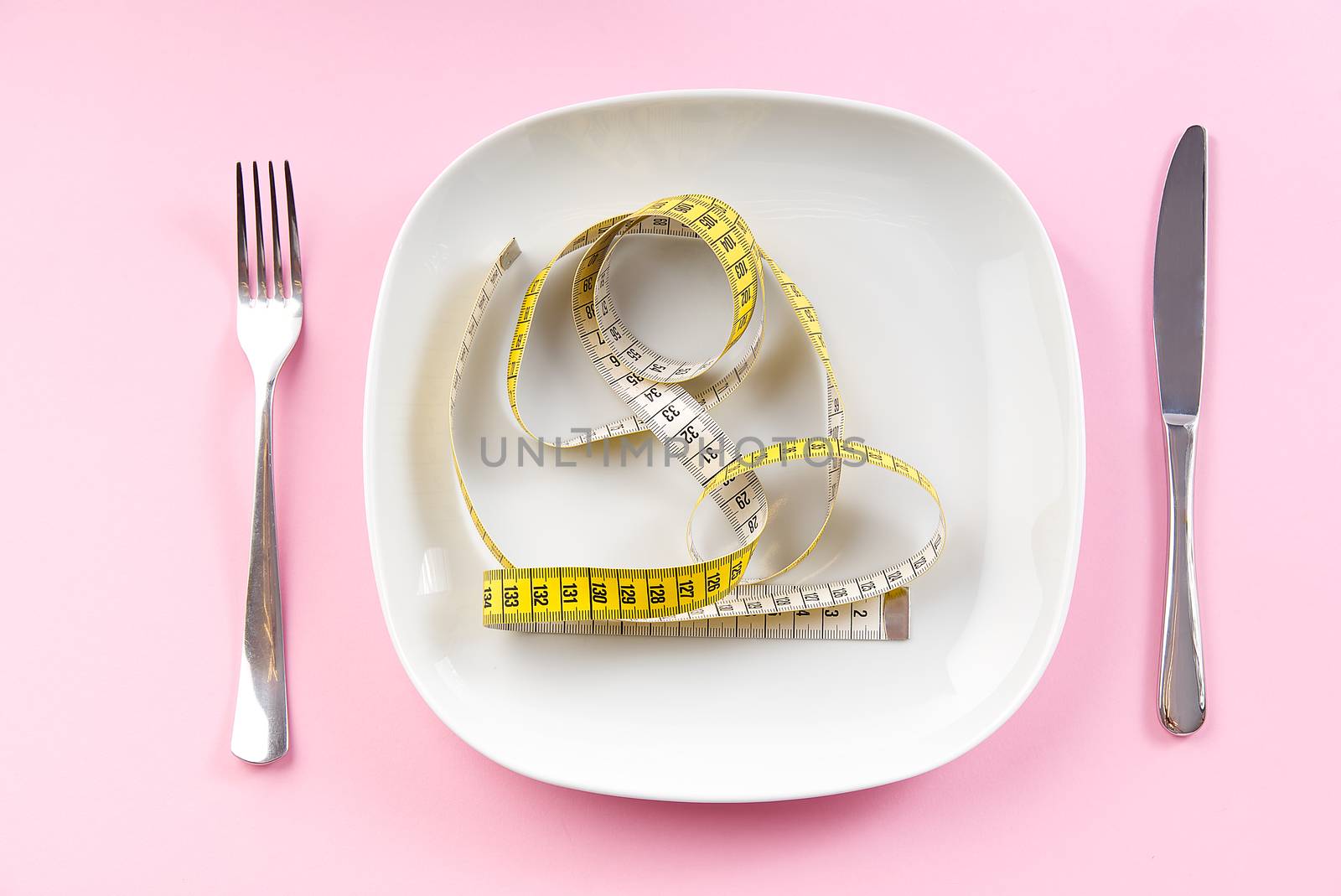Weight Loss Measuring Tape on white plate, concept of healthy dieting. pink Background