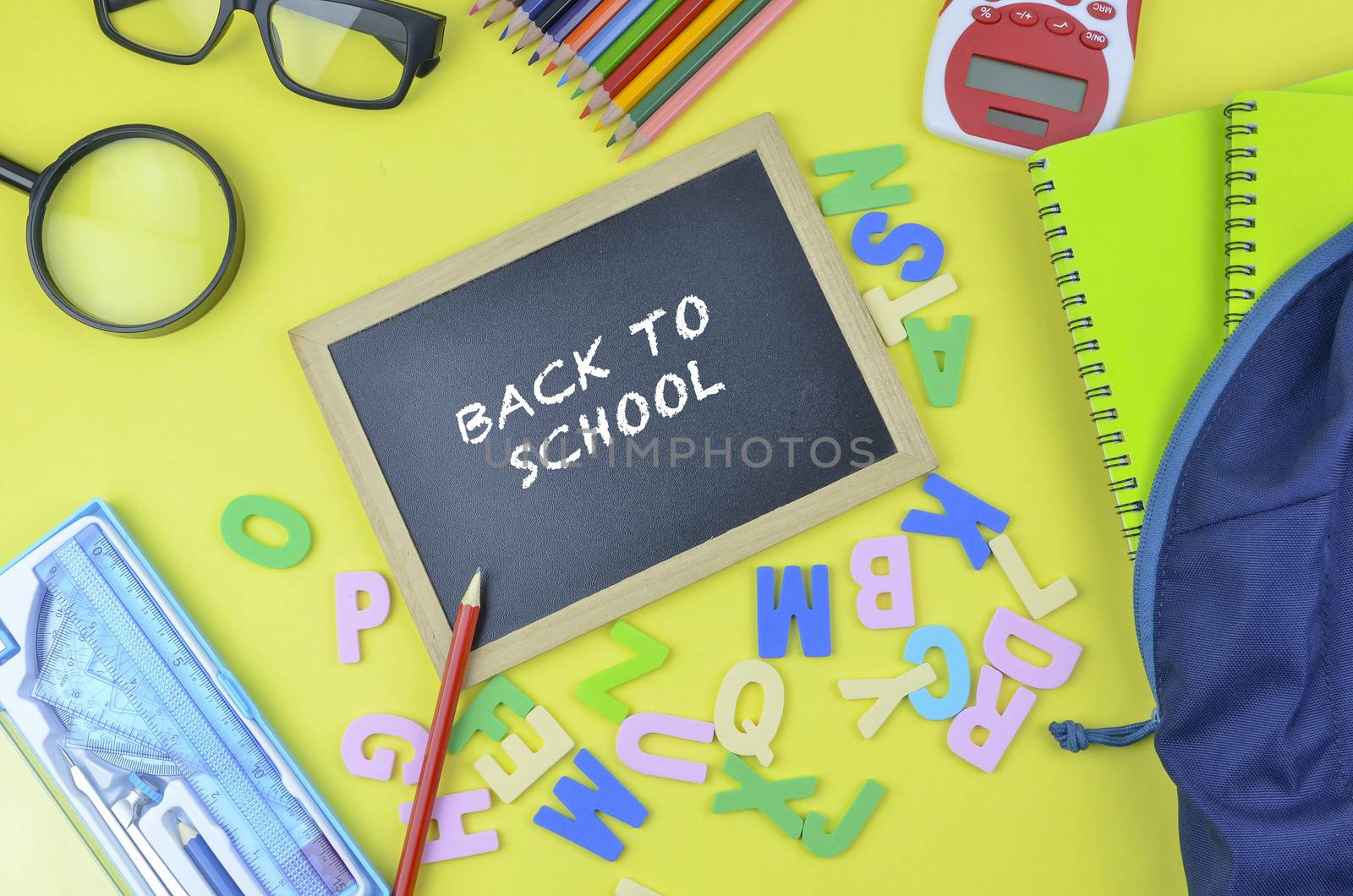 Student backpack and various school supplies. Studying, education and back to school concept. Yellow background and selective focus.