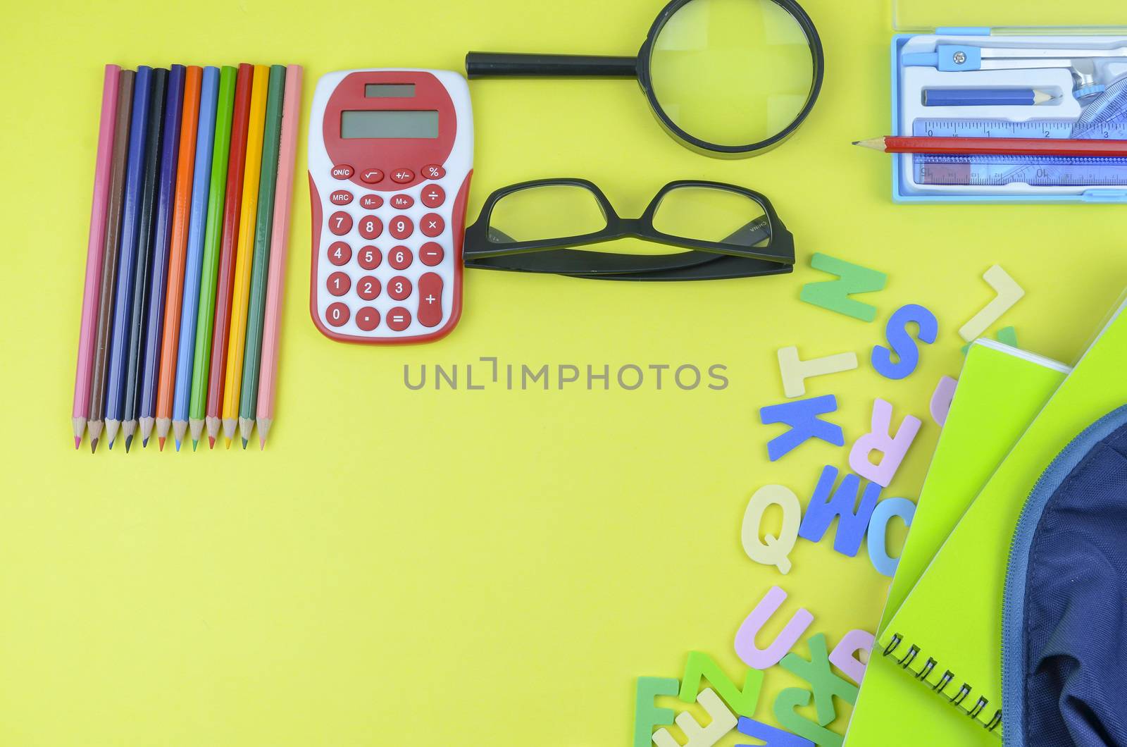 Student backpack and various school supplies. Studying, education and back to school concept. Yellow background and selective focus.