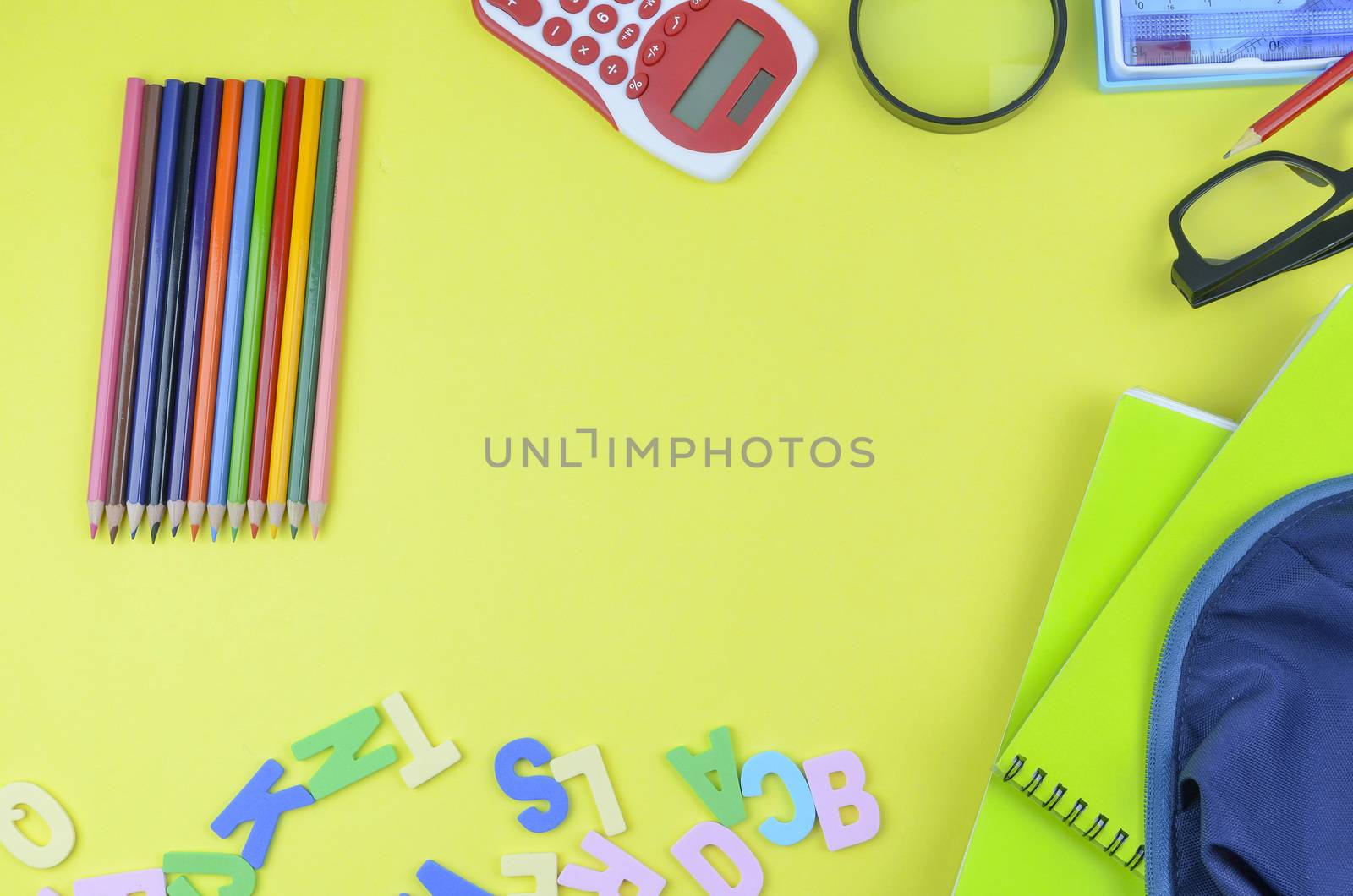 Student backpack and various school supplies. Studying, education and back to school concept. Yellow background and selective focus.