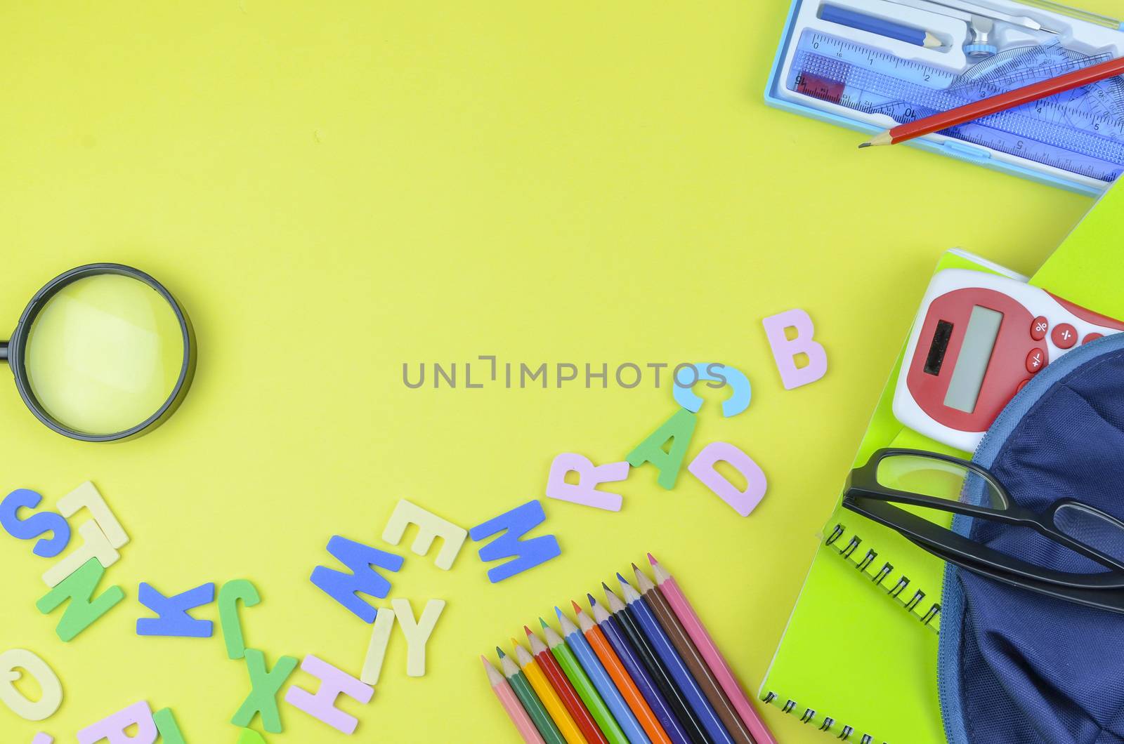 Student backpack and various school supplies. Studying, education and back to school concept. Yellow background and selective focus.