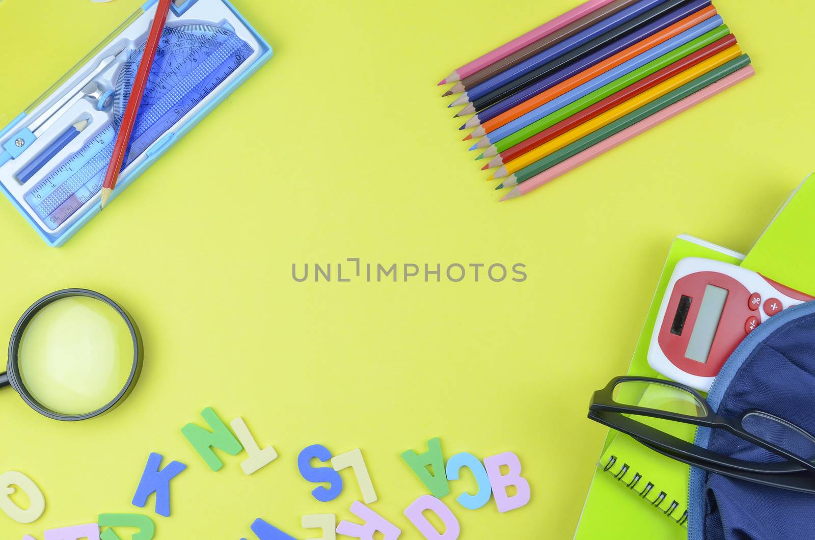 Student backpack and various school supplies. Studying, education and back to school concept. Yellow background and selective focus.