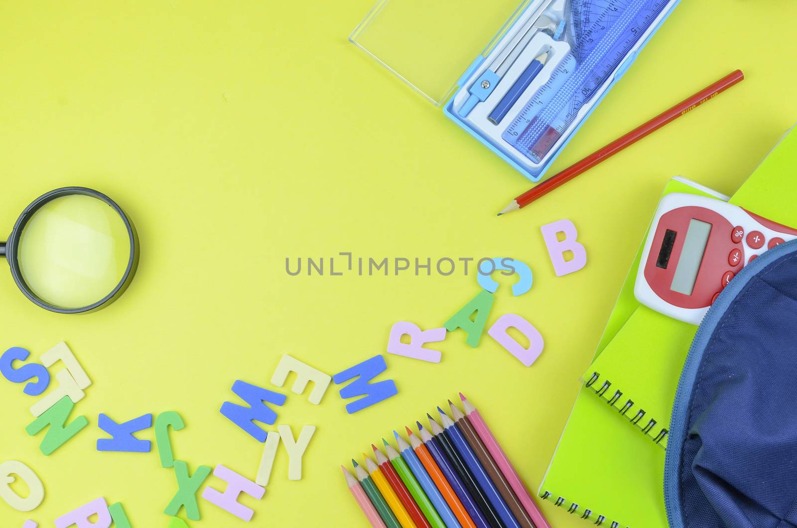 Student backpack and various school supplies. Studying, education and back to school concept. Yellow background and selective focus.