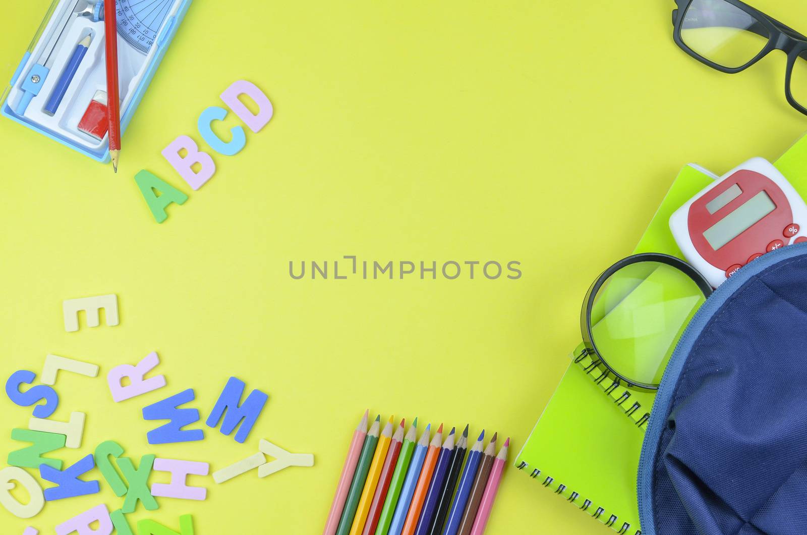 Student backpack and various school supplies. Studying, education and back to school concept. Yellow background and selective focus.