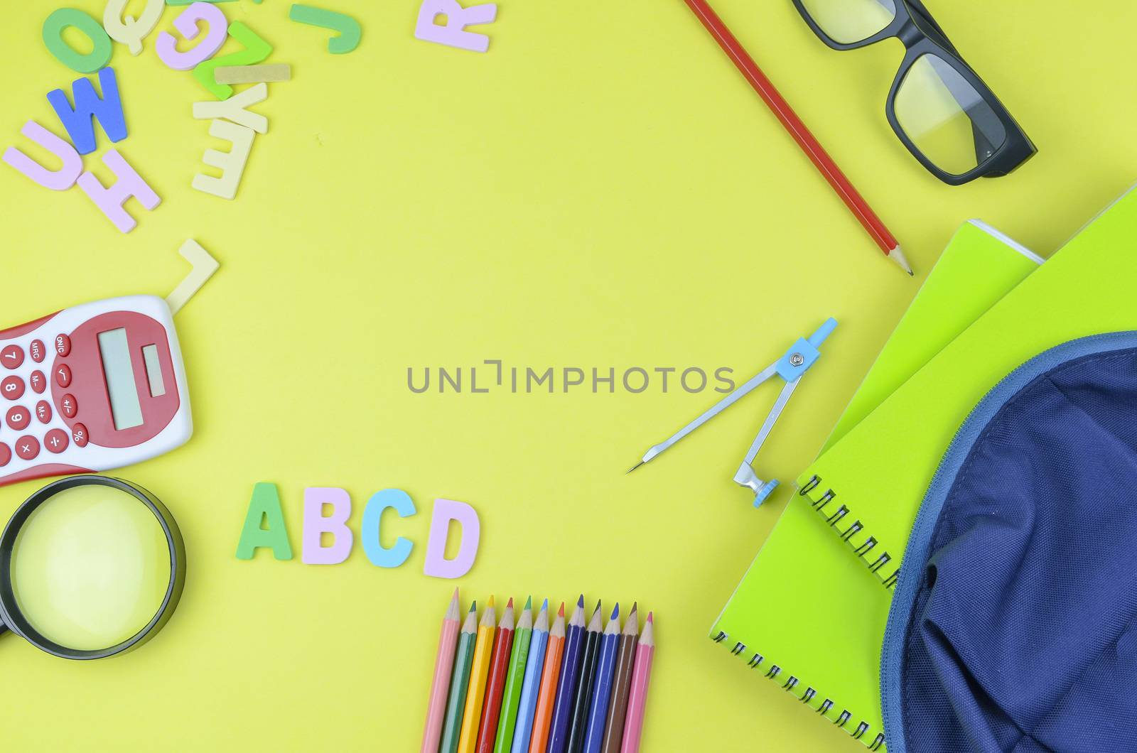 Student backpack and various school supplies. Studying, education and back to school concept. Yellow background and selective focus.